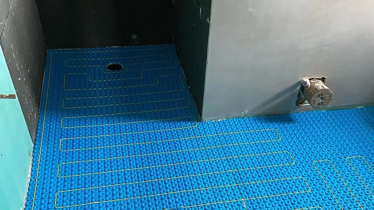 Electric underfloor heating mat installed across a bathroom floor before tiling