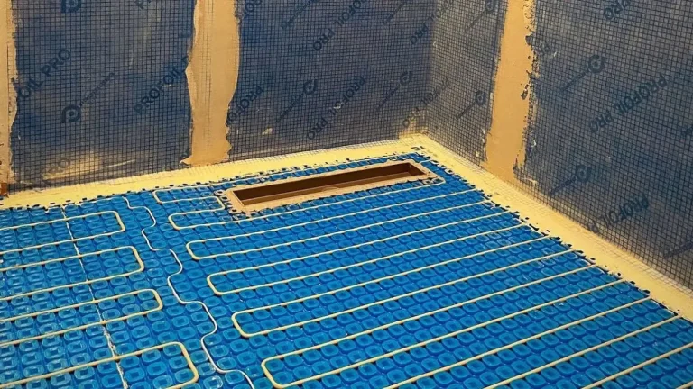 Underfloor heating cables installed over a blue mat in a waterproofed wet room