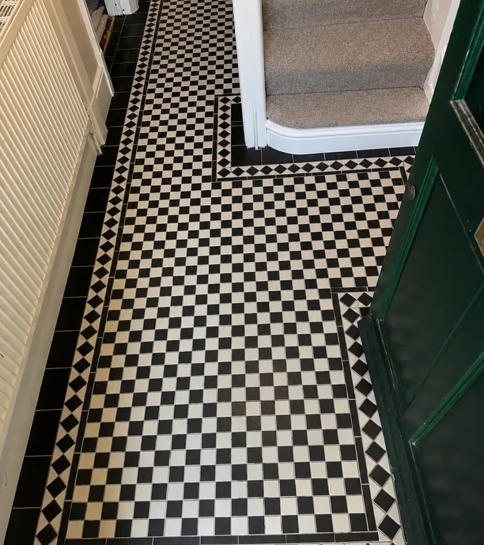 Black and white Victorian checkerboard tiled hallway with geometric border