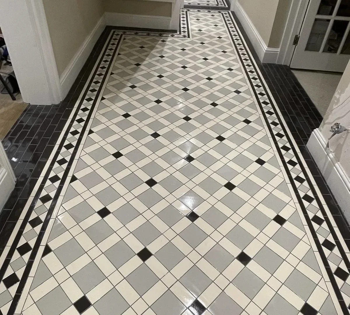 Restored Victorian geometric tiled hallway floor with black and grey border