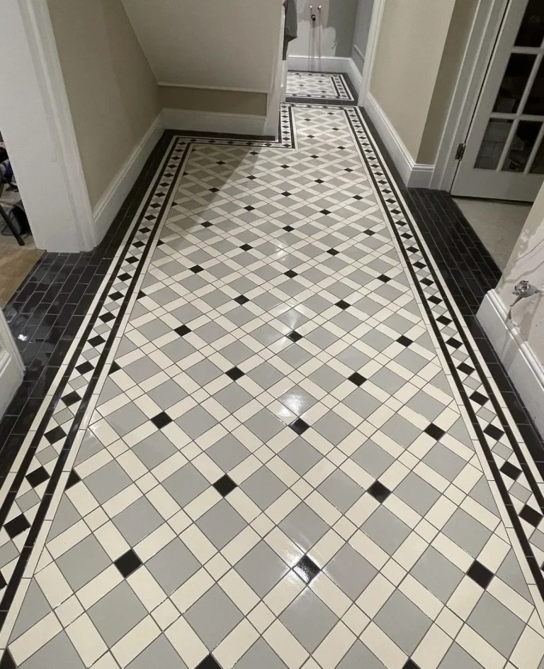 Restored Victorian geometric tiled hallway floor with black and grey border