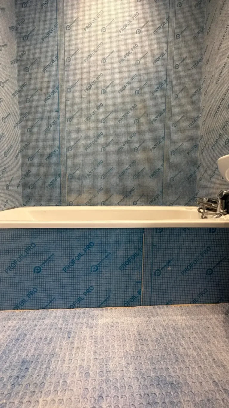 Blue waterproofing membrane around a bath panel and wall before tile installation