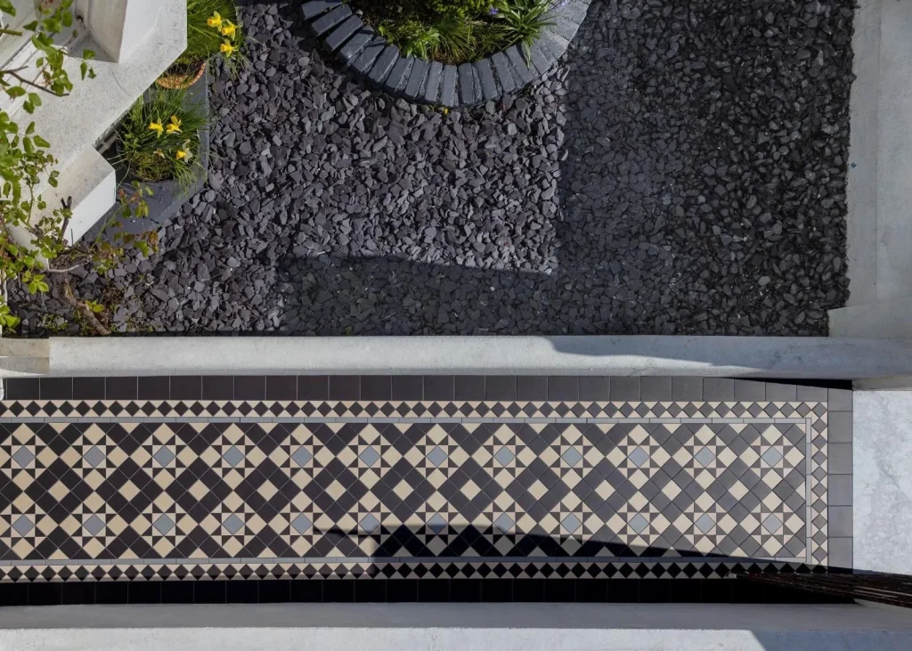 Overhead view of a patterned tiled front path with dark gravel landscaping