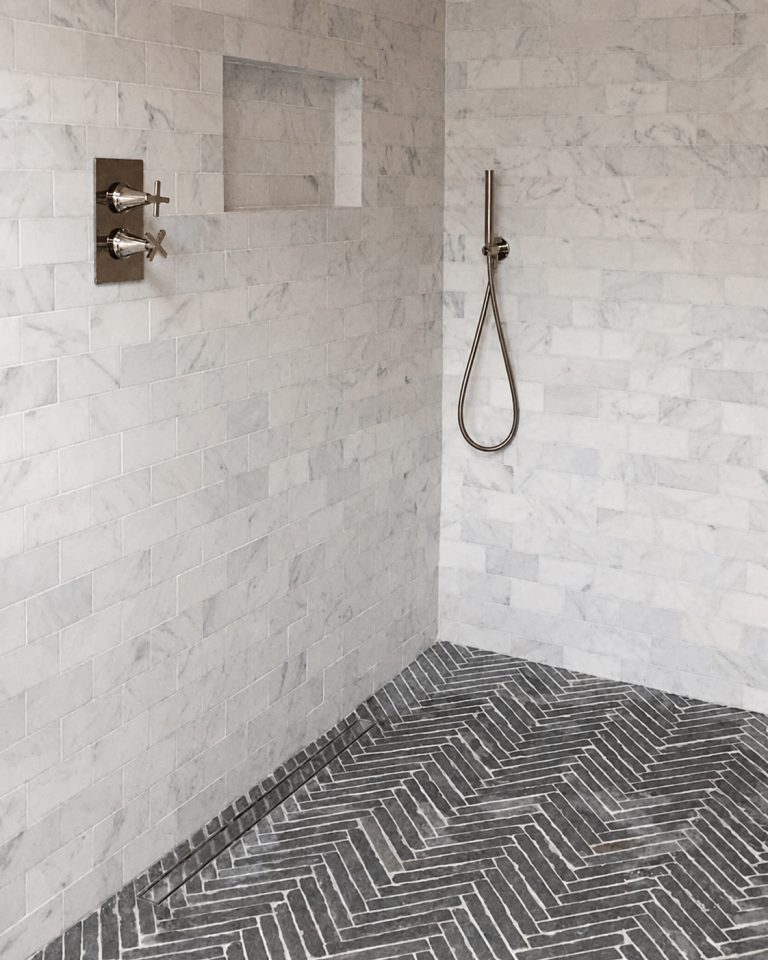 Marble wet room shower with herringbone floor tiles and recessed niche
