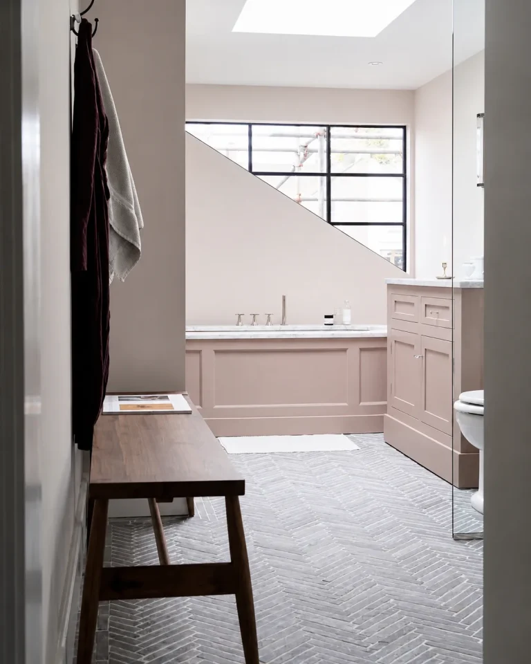 Finished Chiswick en-suite bathroom with pink bath panel, marble vanity and herringbone stone floor by Tile In Progress.