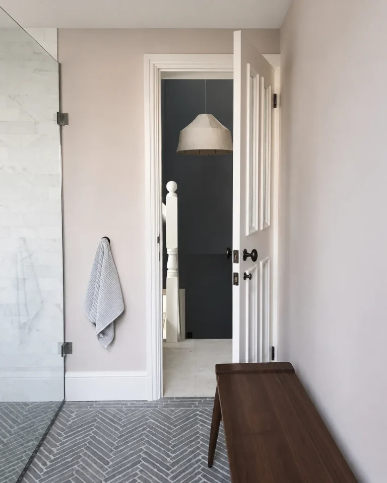 Chiswick en-suite glass shower doorway with timber bench and grey herringbone floor tiles.