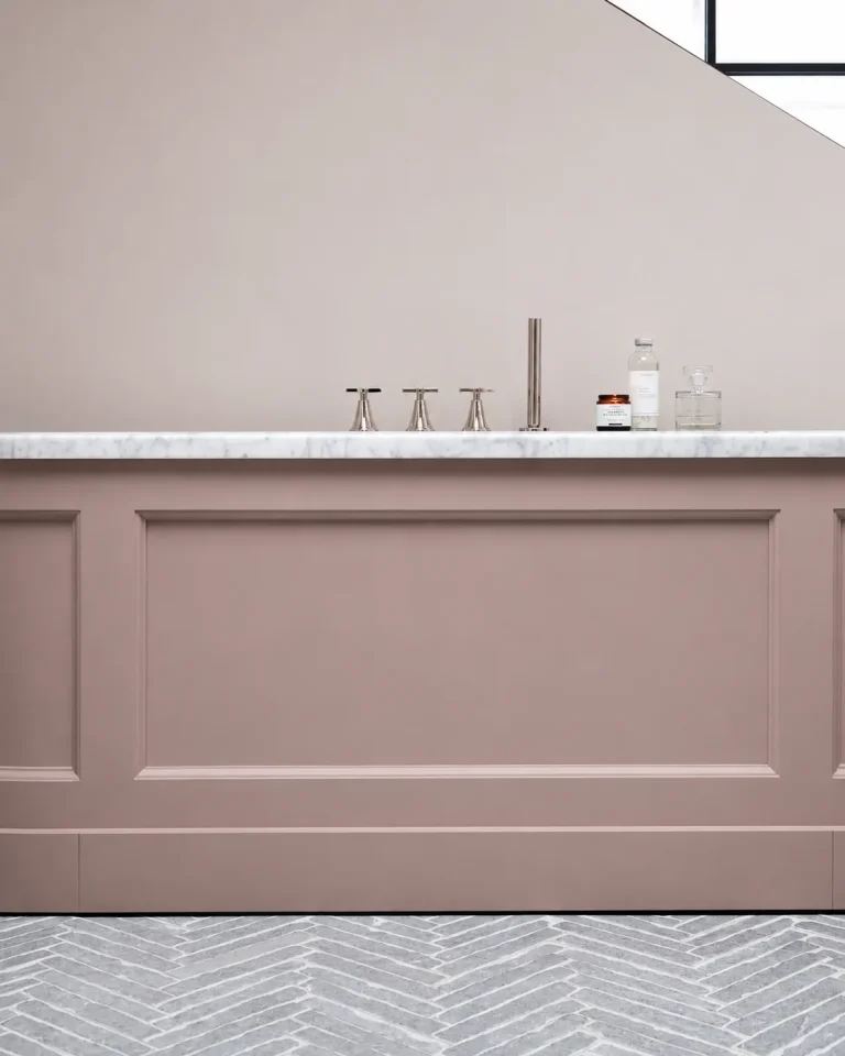 Chiswick en-suite pink bath panel with marble ledge and grey herringbone tiled floor.