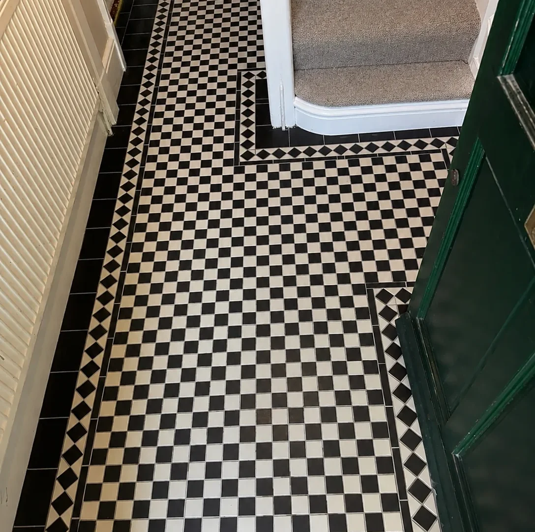 Entrance hallway with black and white checkerboard Victorian floor tiles and green front door.
