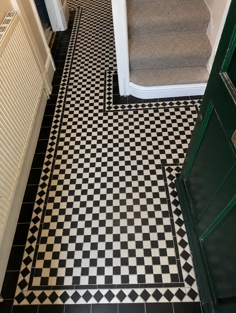 Entrance hallway with black and white checkerboard Victorian floor tiles and green front door.