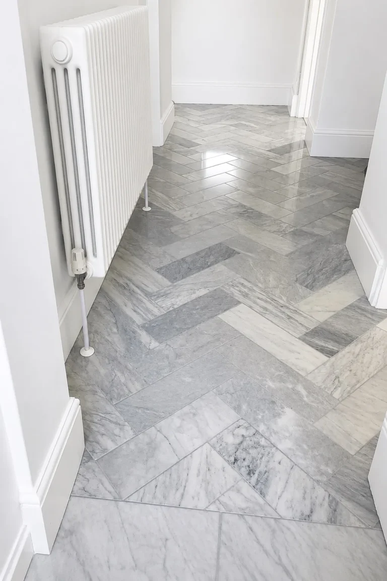 Entrance floor before renovation with grey marble herringbone tiles and white radiator.