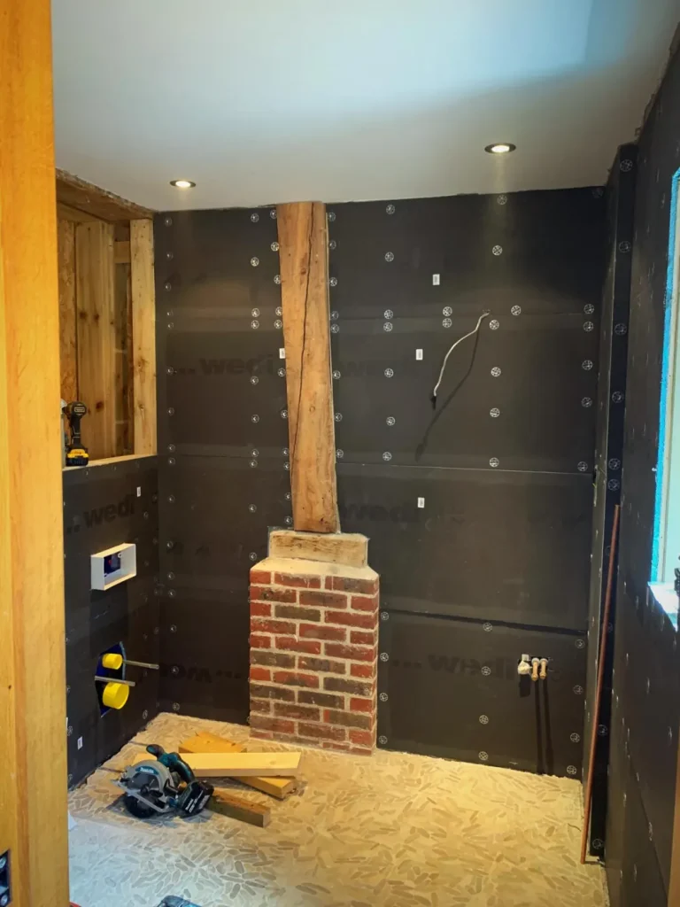 Finished Surrey barn conversion bathroom with walk-in shower, patterned floor tiles and exposed timber beam