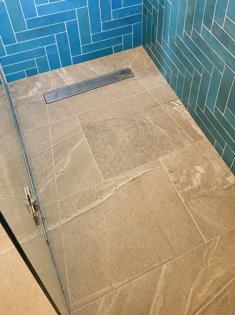 Finished wet room shower floor with blue herringbone tiles in a Twickenham bathroom renovation