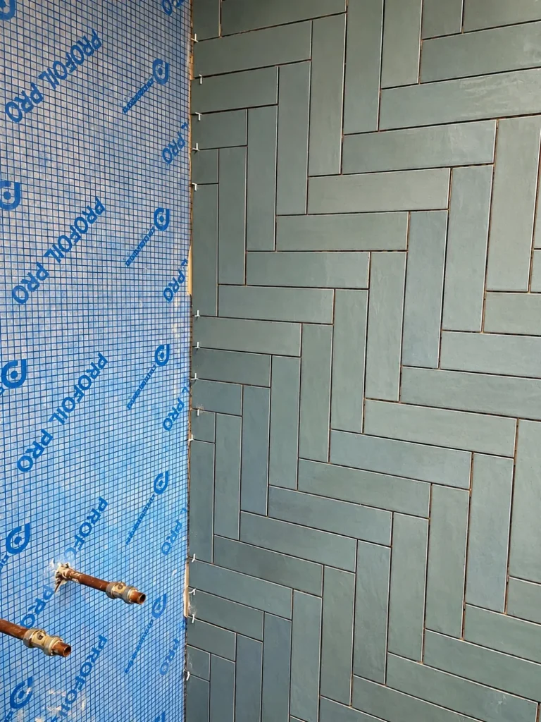 Waterproofing and blue herringbone wall tile installation during a Twickenham bathroom renovation
