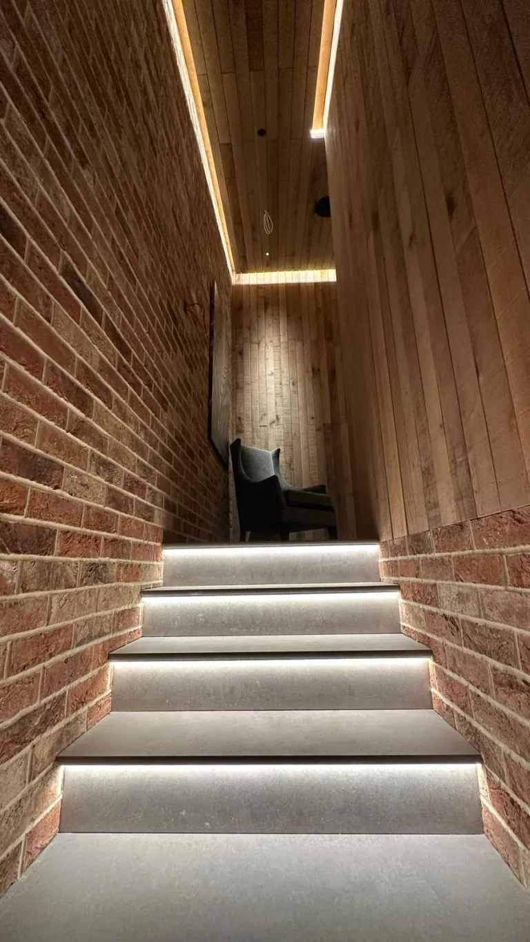Commercial stairwell with brick walls, timber cladding and LED-lit tiled steps