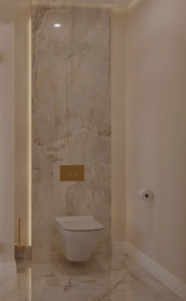 Toilet wall finished in large-format marble-effect tiles with brass flush plate and concealed lighting