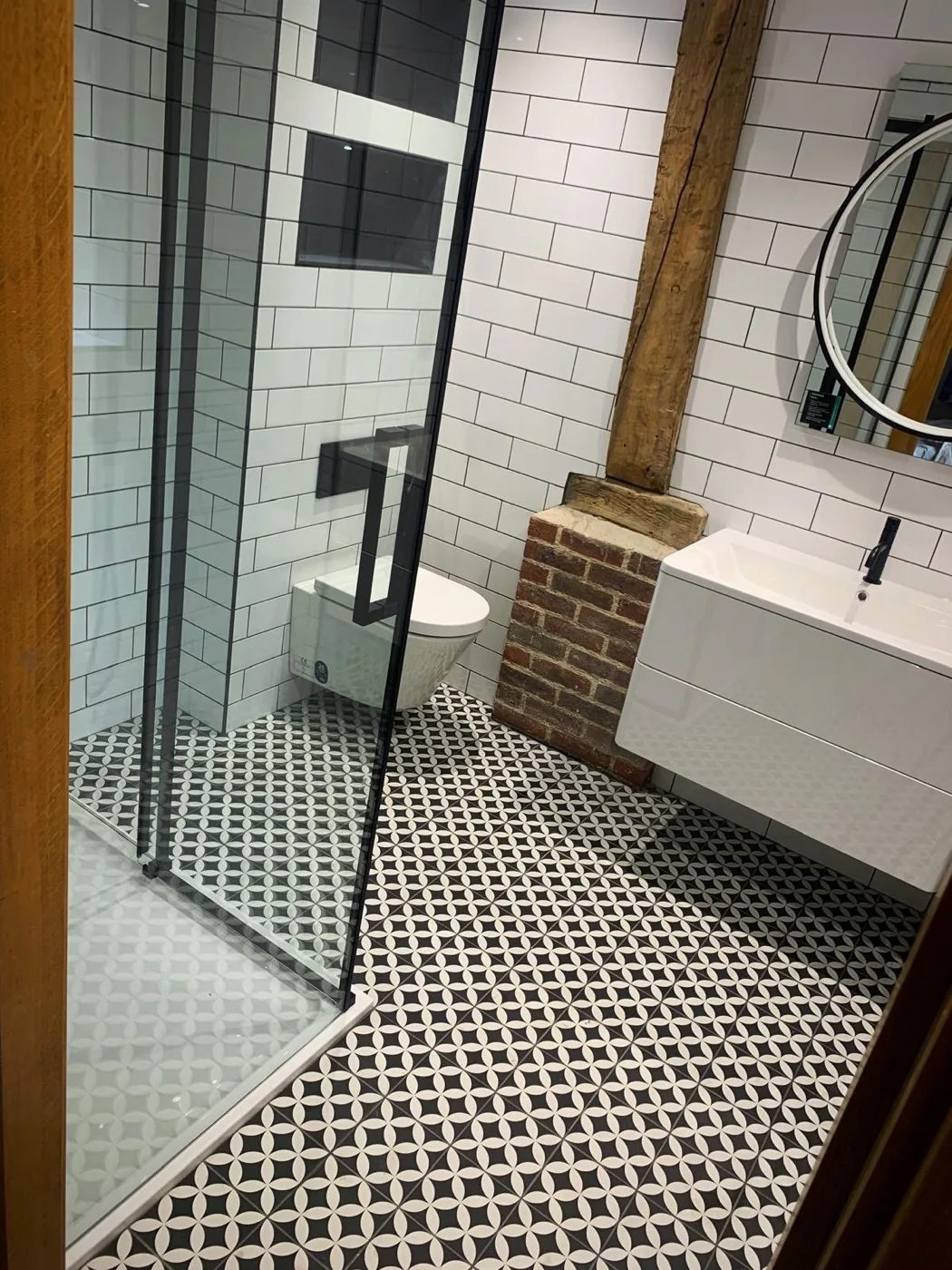 Finished Surrey barn conversion bathroom with white metro tiles, black grout, patterned floor tiles and walk-in shower.